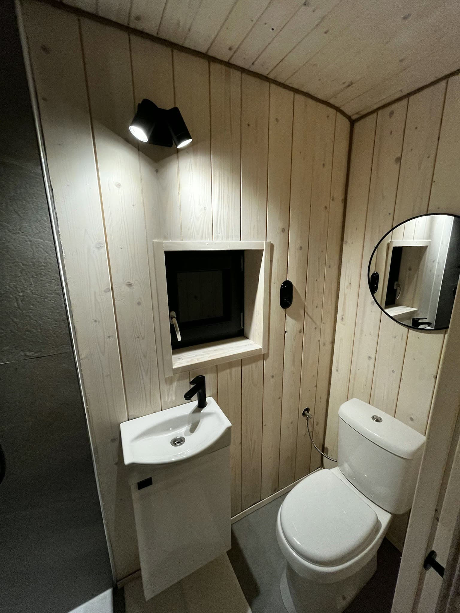 WC, umyvadlo a okno v koupelně se smrkovým obkladem