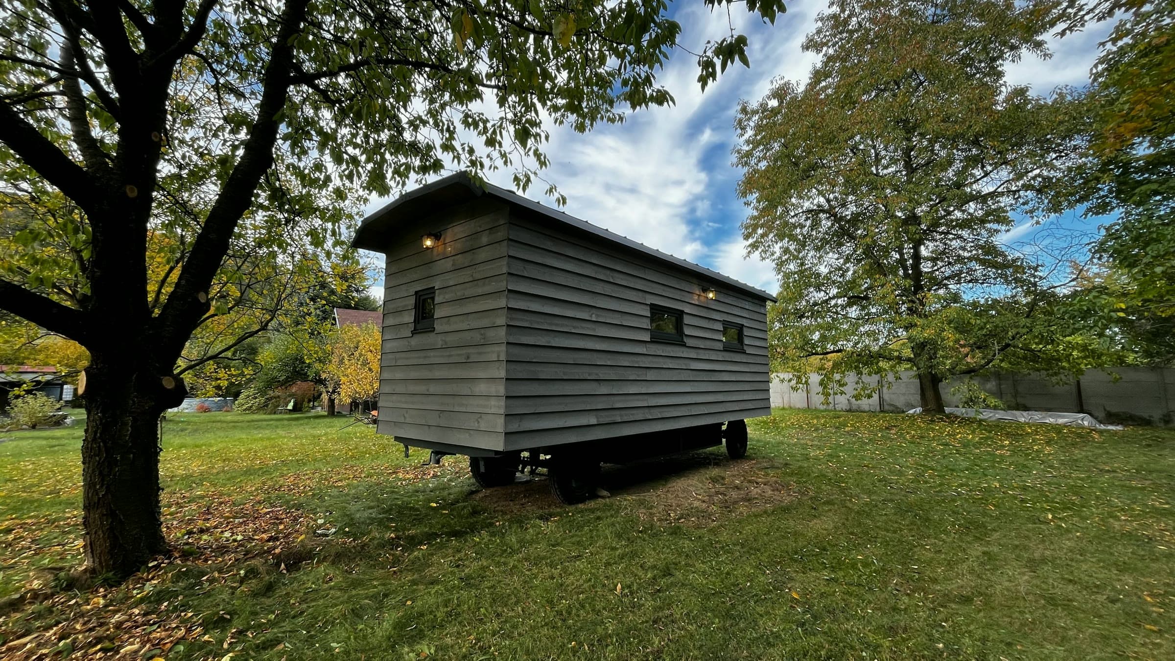 Maringotka ve stínu stromu, šedý dřevěný obklad